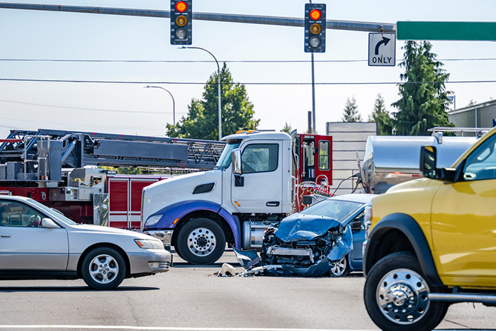 Multi-vehicle accident at an intersection involving a damaged car and trucks
